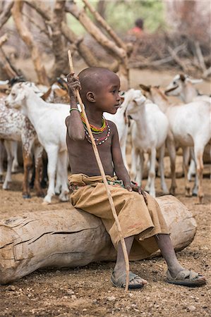 samburu goats - Kenya, Marsabit County, Lasien. A young Samburu girl sits on a log at Lasien wells after her family' s livestock has been watered. Her sandals are made from old rubber tyres. Stock Photo - Rights-Managed, Code: 862-08090675