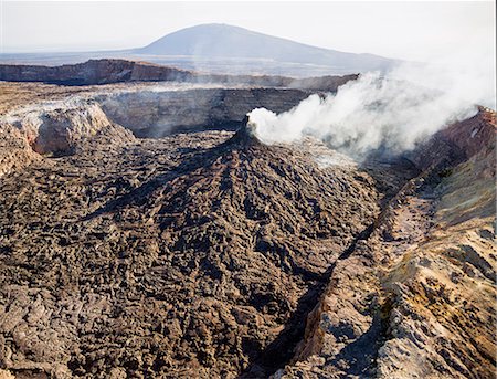 Ethiopia, Erta Ale, Afar Region. The smoking fumarole of one of the two active volcanic pit craters of Erta Ale (foreground) with Borale Ale Volcano in the distance. Stock Photo - Rights-Managed, Code: 862-08273079