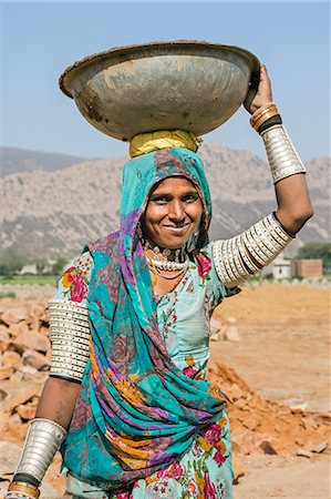 India, Jaysamand, Rajasthan.  A Rajasthani woman with numerous bracelets and armbands carries sand on her head to a building site. Stock Photo - Rights-Managed, Code: 862-08273269