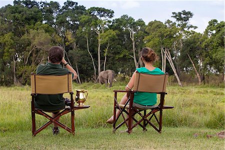 simsearch:862-08273575,k - Kenya, Mara North Conservancy, Elephant Pepper Camp. A couple watch an enormous bull elephant from just outside their tent. Photographie de stock - Rights-Managed, Code: 862-08273552