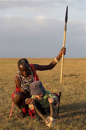 damaliscus korrigum - Kenya, Mara North Conservancy. A young boy examines the skull of a topi antelope under the watchful eye of a Maasai. Stockbilder - Lizenzpflichtiges, Bildnummer: 862-08273602