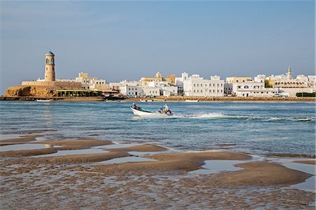 Oman, Al Ayjah, Sur.  A speedboat crosses Sur Bay with the attractive waterfront of Al Ayjah beyond. Foto de stock - Con derechos protegidos, Código: 862-08273742