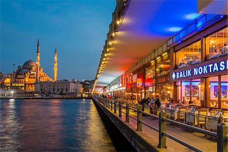 Outdoor restaurants under Galata Bridge with Yeni Cami or New Mosque in the background at dusk, Istanbul, Turkey Fotografie stock - Rights-Managed, Codice: 862-08273901