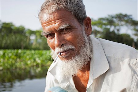 fisherman male old - Jessore, Bangladesh. A traditional boatman transports goods on the tributaries of the Ganges-Brahmaputra delta. Stock Photo - Rights-Managed, Code: 862-08698682