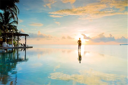 Asia, Cambodia, Sihanoukville, Preah Sihanouk, Koh Rong, Song Saa island resort; woman standing at the edge of an infinity swimming pool against the sunset. MR, PR Stock Photo - Rights-Managed, Code: 862-08698962