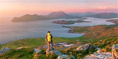 Valentia island (Oilean Dairbhre), County Kerry, Munster province, Ireland, Europe. Panoramic view of a man watching sunset from the Geokaun mountain and Fogher cliffs. Photographie de stock - Rights-Managed, Code: 862-08699412