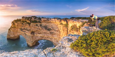 southern portugal - Praia de Marinha, Caramujeira, Lagoa, Algarve, Portugal. Panoramic view of a woman photographing the sunrise from above the cliffs. Stock Photo - Rights-Managed, Code: 862-08699730