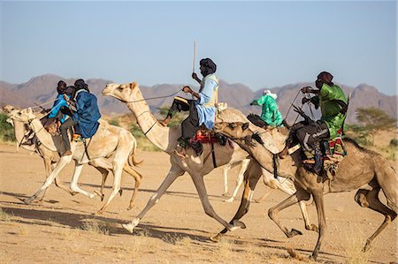 desert camel images - Niger, Agadez, Iferouane. Tuareg men race their camels sitting on traditional three-pronged camel saddles with back rests. Stock Photo - Rights-Managed, Code: 862-08704974