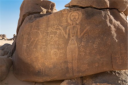 simsearch:862-06676437,k - Niger, Agadez, Touragh. An ancient hunter-gatherer rock engraving of a human figure with raised hands and on the left, smaller figures with a horse and an ostrich. Stock Photo - Rights-Managed, Code: 862-08704973