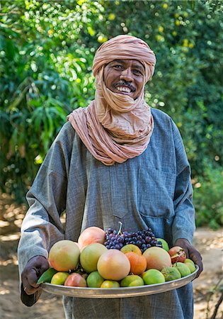 Niger, Agadez, Sub-Sahara, Air Mountains, Timia.  A man holds a bowl of freshly picked fruit at Timia oasis.  The place is renowned for the quality of its grapefruits. Stock Photo - Rights-Managed, Code: 862-08704999
