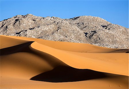Niger, Agadez, Sahara Desert, Tenere, Kogo. Beautiful sand dunes in the Tenere against a mountain backdrop of fractured rocks. Photographie de stock - Rights-Managed, Code: 862-08704991
