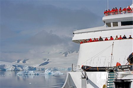 simsearch:862-05999074,k - L'Antarctique, la péninsule Antarctique. Croisière de la côte de l'Antarctique dans le navire de l'expédition, MV Discovery, comme des touristes rouges vêtu parka Découvre les glaciers qui passe et flux depuis le pont de glace. Photographie de stock - Rights-Managed, Code: 862-03288504