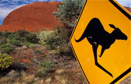 Mise en garde de signe de kangourous à côté d'une route à travers l'Outback, avec les roches rouges de The Olgas derrière le trafic Photographie de stock - Rights-Managed, Code: 862-03288632