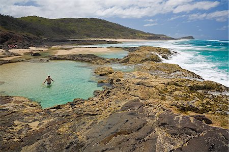 simsearch:862-03288690,k - Un visiteur patauge dans une piscine de roche naturelle bordant l'océan, sur la pointe orientale du Nord de l'île de Fraser. La zone connue comme Champagne Pools est l'eau de mer uniquement sécuritaire nage comptant sur l'île. Photographie de stock - Rights-Managed, Code: 862-03288700