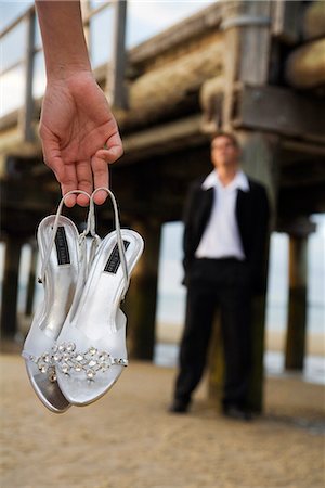 Eine Frau hält ihren high Heels auf dem Strand Sand, während ihr Partner unter den Pier in Kingfisher Bay blickt auf. Stockbilder - Lizenzpflichtiges, Bildnummer: 862-03288756