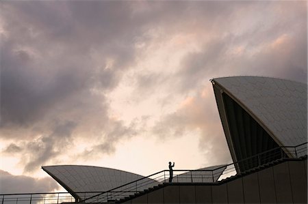 simsearch:862-03289180,k - Un visiteur est éclipsé par les toits en forme de voile de l'emblématique opéra de Sydney Photographie de stock - Rights-Managed, Code: 862-03288808