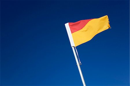 The iconic red and yellow flag of Australian lifesaving. Pairs of flags are used to mark areas of the beach patrolled by lifesavers and safe for swimming Stock Photo - Rights-Managed, Code: 862-03288856