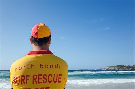 A lifesaver watches the surf on Bondi Beach in eastern Sydney. Lifesavers are a common sight on Australian beaches,assisting swimmers in distress. Foto de stock - Direito Controlado, Número: 862-03288859