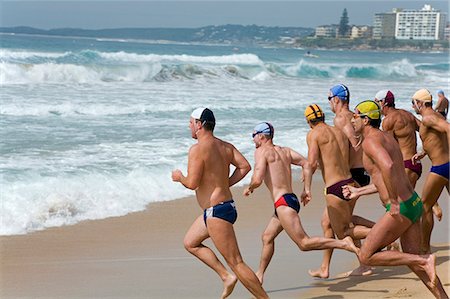 racing brief - Lifesavers wearing the colours of their respective clubs sprint to the water during a swimming race at the New South Wales Lifesaving Championships at Cronulla Beach. Stock Photo - Rights-Managed, Code: 862-03288868