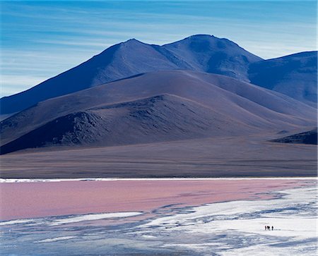 simsearch:862-03289428,k - A group of tourists walk along the fringe of Laguna Colorada. The distinctive red colour of this high altitude lagoon is due to the high concentration of algae whilst deposits of borax form a white fringe to the lake. Colorada is the biggest nesting site of the rare James flamingo and also hosts large concentrations of Chilean and Andean flamingos. Foto de stock - Con derechos protegidos, Código: 862-03289456