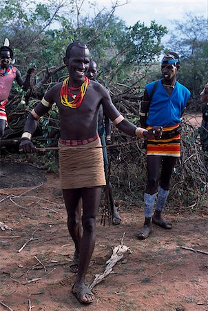 A Hamar warrior tests the whippiness of a switch prior to the bull -jumping ceremony of a man in their family,a rite of passage to manhood. The women of the family will volunteer themselves to be whipped by the warriors present as a sign of their love and devotion to the bull-jumper. Foto de stock - Con derechos protegidos, Código: 862-03354055