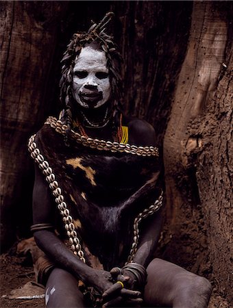 simsearch:862-03354090,k - A Karo woman wears an elaborate headdress made from the wing-cases of beetles and a cape of calf skin fringed with cowrie shells. A small Omotic tribe related to the Hamar,who live along the banks of the Omo River in southwestern Ethiopia,the Karo are renowned for their elaborate body painting using white chalk,crushed rock and other natural pigments. Stock Photo - Rights-Managed, Code: 862-03354096