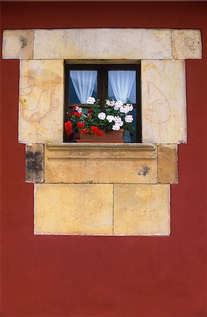 simsearch:862-03354288,k - An old stone window with a carved stone cill is decorated with flowers and framed by the red painted walls of a mansion in Llanes Foto de stock - Direito Controlado, Número: 862-03354298