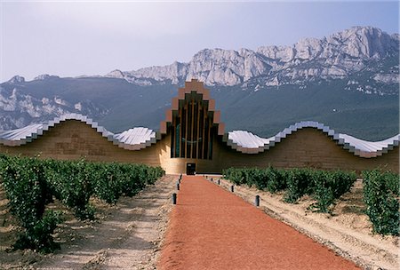 The striking architecture of Ysios winery,designed by world renowned architect Santiago Calatrava,mirrors the undulations of the limestone mountains of the Sierra de Cantabria rising behind Stock Photo - Rights-Managed, Code: 862-03354359