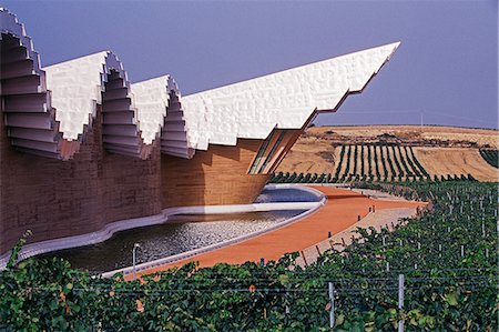 The striking centre-piece Ysios winery,designed by world renowned architect Santiago Calatrava,protrudes from the undulating aluminium roof like the prow of a ship Ysios Winery designed by Santiago Calatrava,Leza Alava,Spain Foto de stock - Con derechos protegidos, Código: 862-03354365