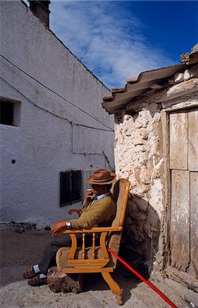 simsearch:862-03354518,k - Spain,Andalucia,Sierra de Segura,Hornos (aka Hornos de Segura). A man enjoys a cigarette on a sofa outside his house. Foto de stock - Con derechos protegidos, Código: 862-03354546