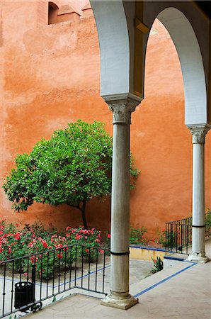 simsearch:862-03354518,k - Espagne, Andalousie, Séville. La grève en terre cuite de couleur murs d'une cour intérieure dans les contrastes de l'Alcazar avec le cadre verdoyant d'un arbre d'agrumes. Photographie de stock - Rights-Managed, Code: 862-03354542