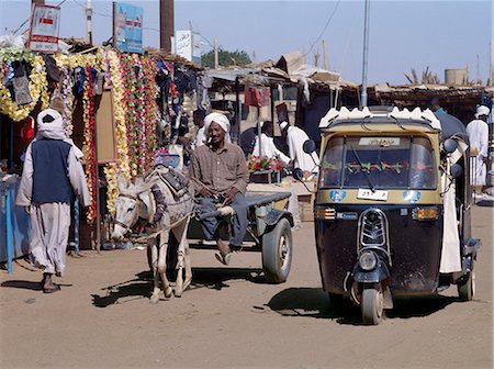 donkey carts africa - Ancient and modern transport plys the dusty streets of the important market town of Karima. Indian-made three-wheeled Bajaj taxis have become popular forms of modern transport in towns throughout The Sudan. Stock Photo - Rights-Managed, Code: 862-03354593