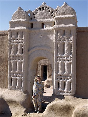 A Nubian girl stand in an archway at the village of Qubbat Selim. Traditional Nubian architecture. Traditional Nubian architecture and plasterwork of a fine archway to a house and its courtyard at Qubbat Selim. Fotografie stock - Rights-Managed, Codice: 862-03354605