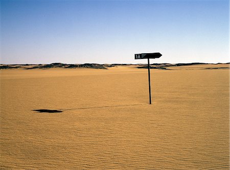 Un vieux poteau indicateur marque une piste abandonnée dans le désert de Nubie, au nord de Old Dongola. Elle est marquée en arabe « 108 », qui est probablement le kilométrage de Karima à Dongola. Le parcours à travers le désert se déroule maintenant au moins 10 km de l'enseigne. Photographie de stock - Rights-Managed, Code: 862-03354629