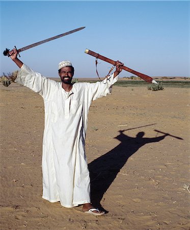 simsearch:862-03820977,k - Un homme nubien affiche son épée dans une oasis dans le désert de Nubie au nord de Old Dongola. Photographie de stock - Rights-Managed, Code: 862-03354634