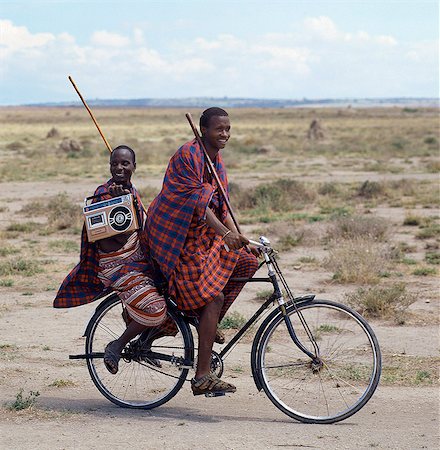 Old and new. Dressed traditionally and carrying familiar wooden staff,two young men give hints that the lifestyle of younger Maasai generations is changing gradually in Tanzania. Foto de stock - Direito Controlado, Número: 862-03355128