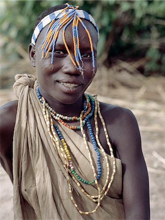 A Hadza girl wearing a beaded headband and necklaces.The Hadzabe are a thousand-strong community of hunter-gatherers who have lived in the Lake Eyasi basin for centuries. They are one of only four or five societies in the world that still earn a living primarily from wild resources. Foto de stock - Con derechos protegidos, Código: 862-03355175