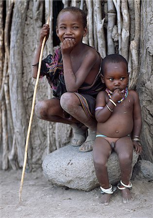 Deux jeunes garçons de Datoga. Le plus jeune porte métalliques cloches autour de ses chevilles pour s'assurer qu'il ne pas errer loin de chez eux sans sa mère ou un autre membre de la famille entendu. Le Datoga (connu pour leurs voisins Maasai comme le Mang'ati et le Iraqw comme Babaraig) vivent dans le nord de la Tanzanie et sont principalement des éleveurs. Photographie de stock - Rights-Managed, Code: 862-03355177