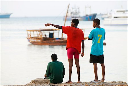 simsearch:851-02963338,k - East Africa; Tanzania. Locals watching boats & Dhows coming into Stonetown Harbour,Zanzibar. Stock Photo - Rights-Managed, Code: 862-03355278