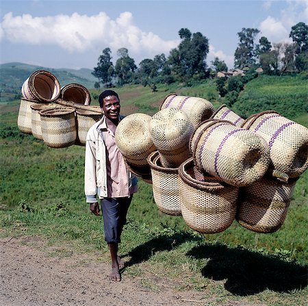 A man carries traditional split-bamboo baskets to sell at Kisoro market. Most women in Southwest Uganda carry their farm produce to market in these attractive baskets balanced on their heads. Basket-making is the sole preserve of men. Stock Photo - Rights-Managed, Code: 862-03355424