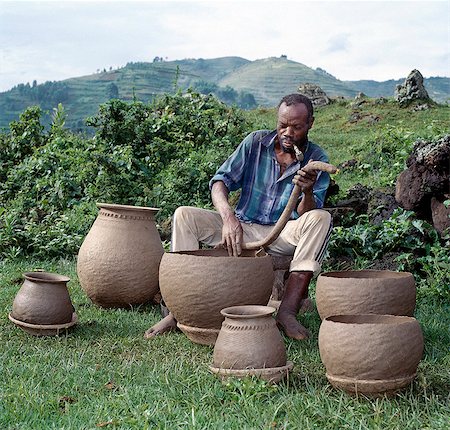 A potter fashions cooking pots by the coil method,shaping them by eye alone. Surprisingly,craft skills such as pottery and basket-making are the sole preserve of men in Southwest Uganda. Stock Photo - Rights-Managed, Code: 862-03355426