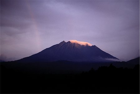 Mount Sabinyo (11,923 feet) is one of three volcanoes of the Virunga chain bordering Uganda. Its name in the local language means father with huge teeth because a row of five sharp rock pinnacles give the appearance of protruding from a long,curved jawbone (its summit ridge) Foto de stock - Con derechos protegidos, Código: 862-03355436