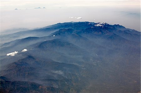 simsearch:862-03808741,k - Uganda. An aerial view of the Ruwenzori Mountains taken from the north of the 70-mile-long range with the peaks of the Virunga Volcanoes visible above the clouds in the far distance. The permanent snow-covered peaks of the Rwenzoris straddle the Uganda-Congo DRC border in the centre of the range. Foto de stock - Direito Controlado, Número: 862-03355439