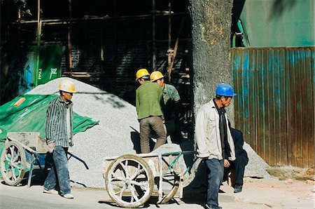 China,Beijing. Construction workers carrying wheel barrows. Stock Photo - Rights-Managed, Code: 862-03351335