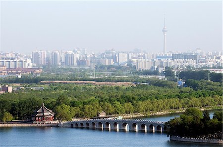 China,Beijing. Summer Palace - Unesco World Heritage Site. The 17 arch bridge and city skyline. Stock Photo - Rights-Managed, Code: 862-03351443