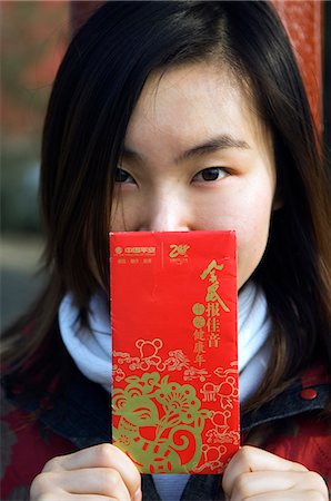 Chine, Beijing. Une fille chinoise, porter des vêtements de style traditionnel chinois détenant une enveloppe Hongbao qui est reçue avec de l'argent par les étudiants et les enfants pendant le Festival de printemps pour le nouvel an chinois. Photographie de stock - Rights-Managed, Code: 862-03351514