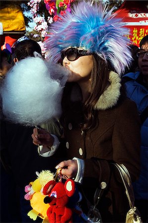 simsearch:862-03351558,k - China,Beijing. Chinese New Year Spring Festival - Ditan Park temple fair A girl eating candy floss and wearing a costume hat. Stock Photo - Rights-Managed, Code: 862-03351559