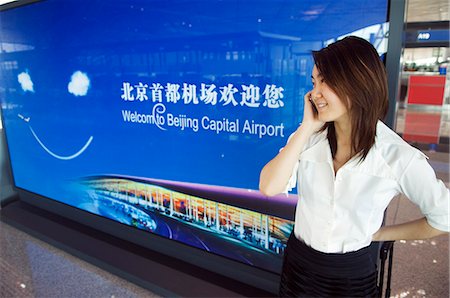 peking airport - China,Beijing,Beijing Capital Airport. A Chinese business woman in the new Terminal 3 building opened February 2008,second largest building in the world . Stock Photo - Rights-Managed, Code: 862-03351599