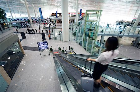 escalators china - China,Beijing,Beijing Capital Airport. A Chinese business woman in the new Terminal 3 building opened February 2008,second largest building in the world . Stock Photo - Rights-Managed, Code: 862-03351603