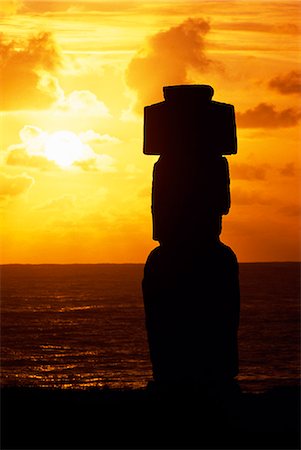 À Ahu Kote Riku, un seul moai bien conservé se détache au coucher du soleil car elle se situe sur le dessus de le trois ahus ou plates-formes de centre cérémoniel de Tahai. Tahai est juste à quelques pas de la principale agglomération de l'île de Pâques, Hanga Roa sur la côte ouest de l'île, soutenu par l'océan Pacifique. Photographie de stock - Rights-Managed, Code: 862-03352097